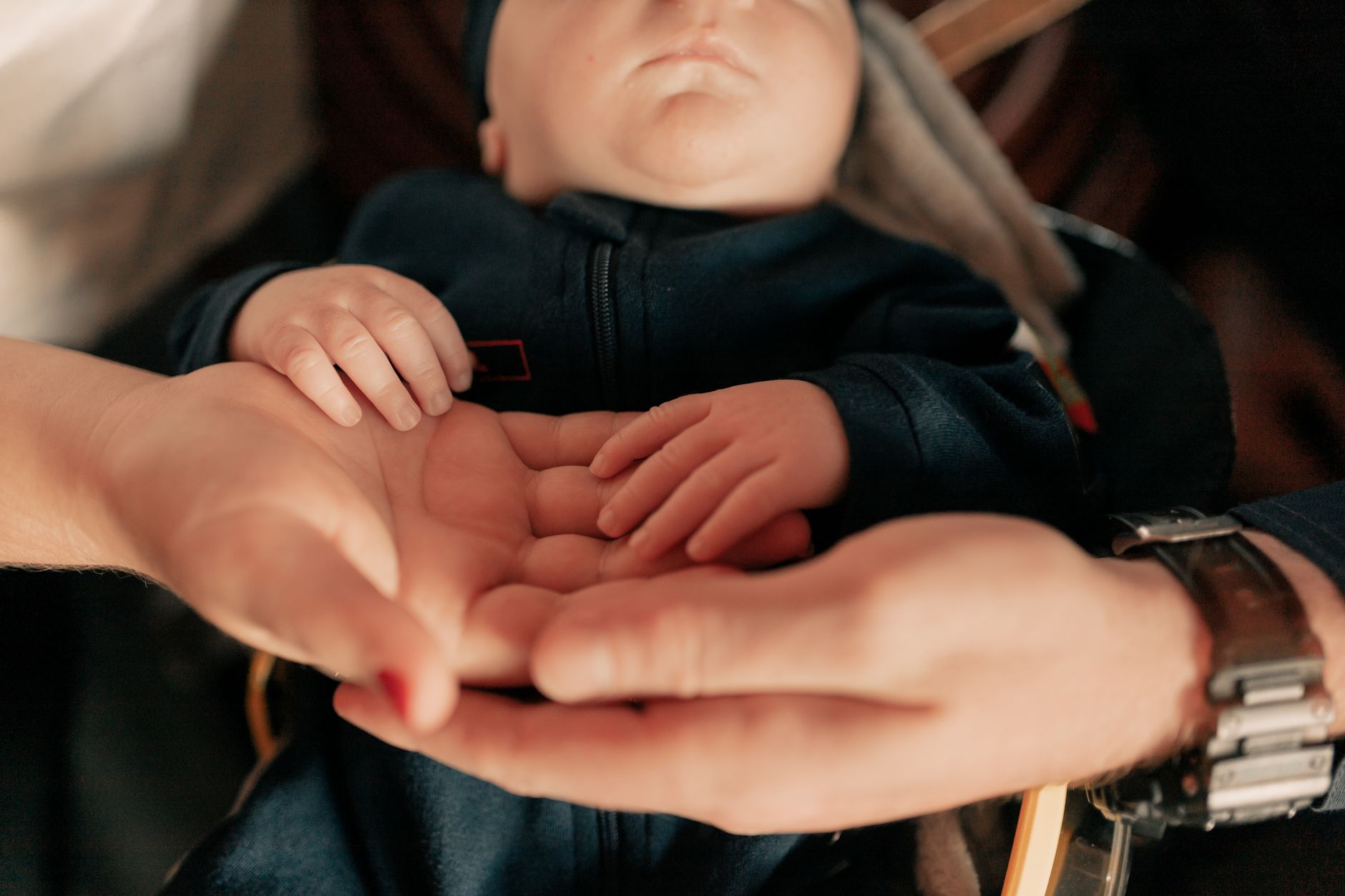 Two adult hands cradling a newborn&rsquo;s hands. Stock photograph.